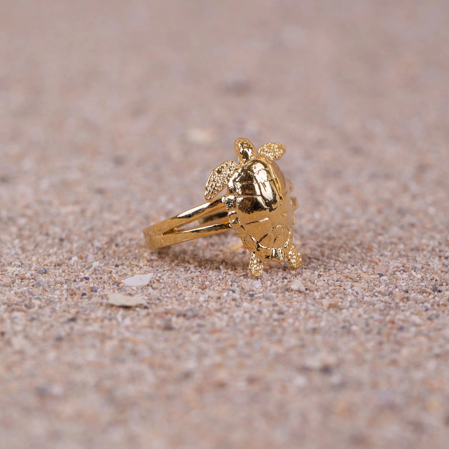 Anillo Cayume bañado en Oro en macro sobre arena.