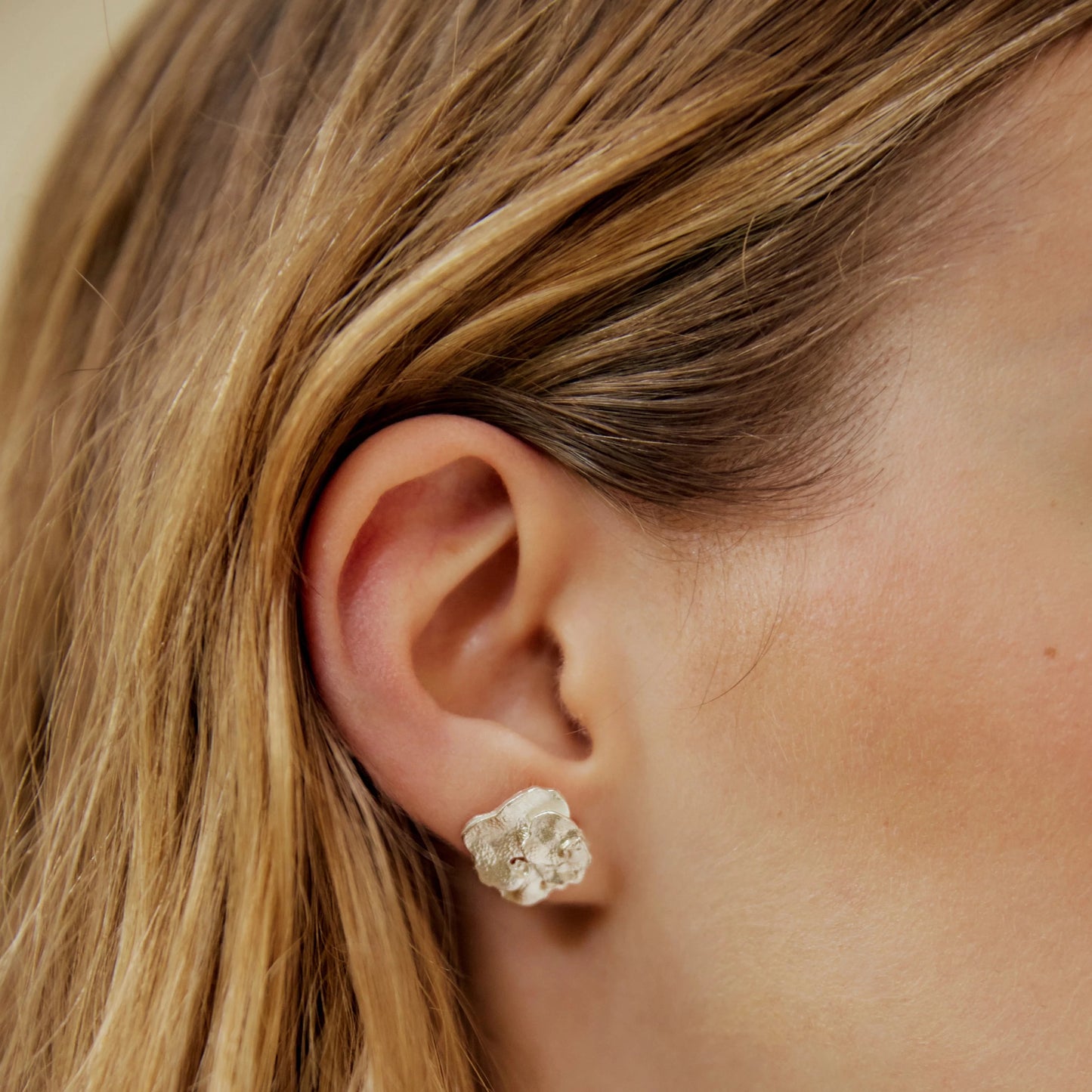 Detalles de la modelo luciendo en la oreja el Pendiente de botón de Pétalo en Plata.