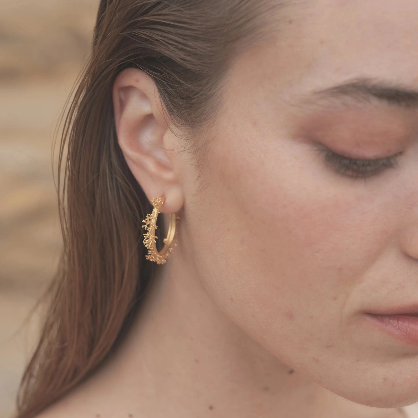 Modelo morena luciendo los Aros de Coralina bañados en Oro.