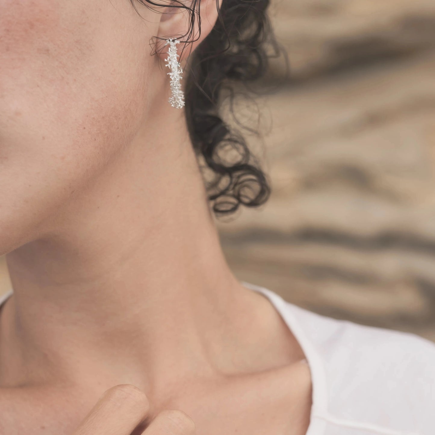 Detalles de los Aros Coralina en Plata puestos en una modelo morena ligeramente de perfil.