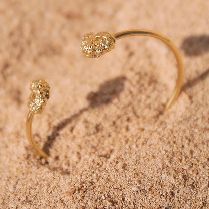 Brazalete de Esponja bañado en Oro en macro parcialmente hundido en la arena.