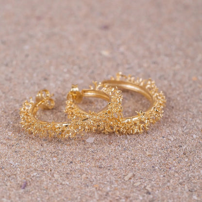 Aros de Coralina bañados en Oro posados en la arena uno encima del otro 