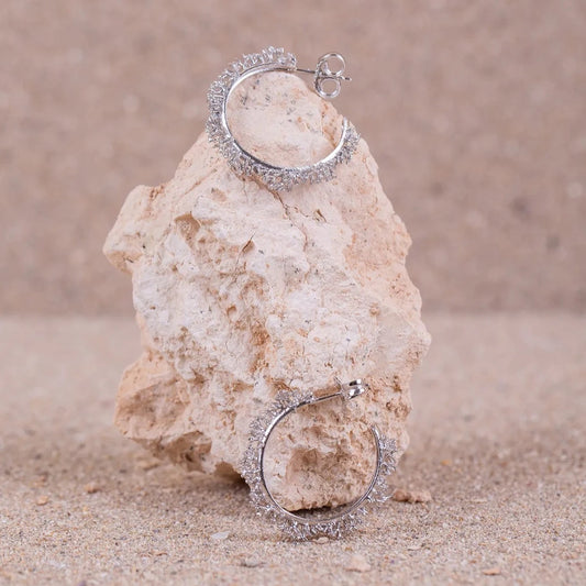 Detalles en macro de los Aros de Coralina en Plata ambos posados sobre una roca.