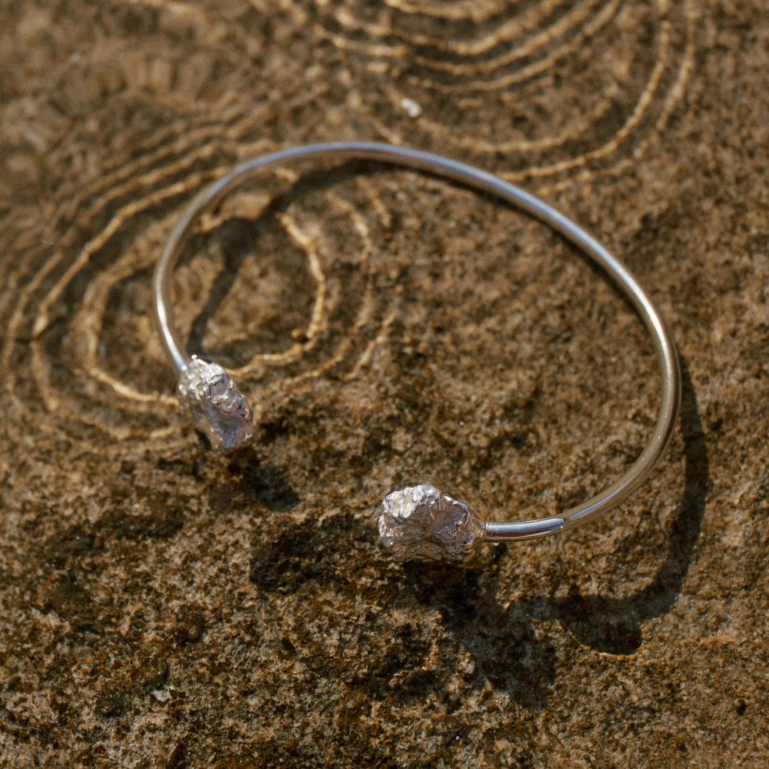 Brazalete Esponja de Plata en Macro sobre el agua con ondulaciones en ella.