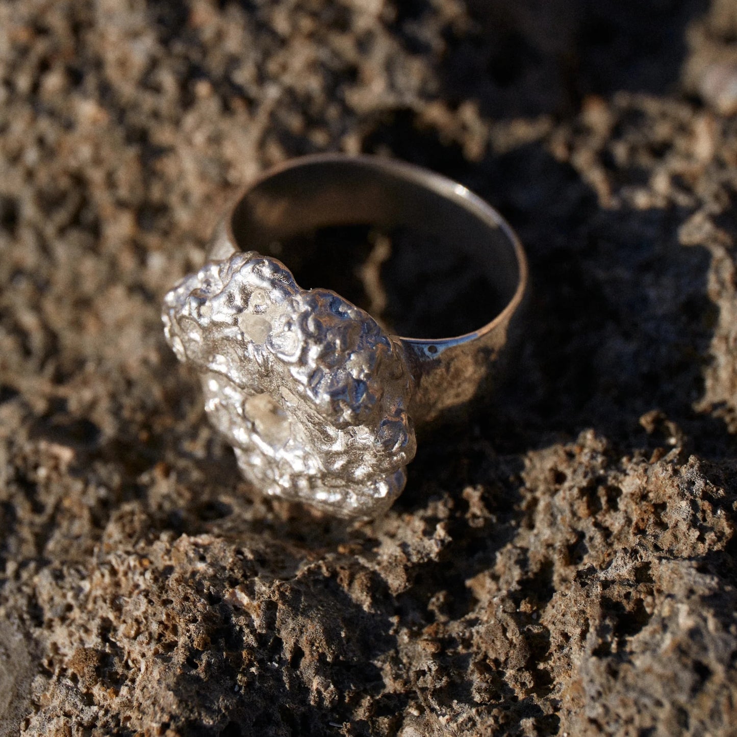 Detalles en macro del Anillo de Esponja en Plata sobre rocas marinas.
