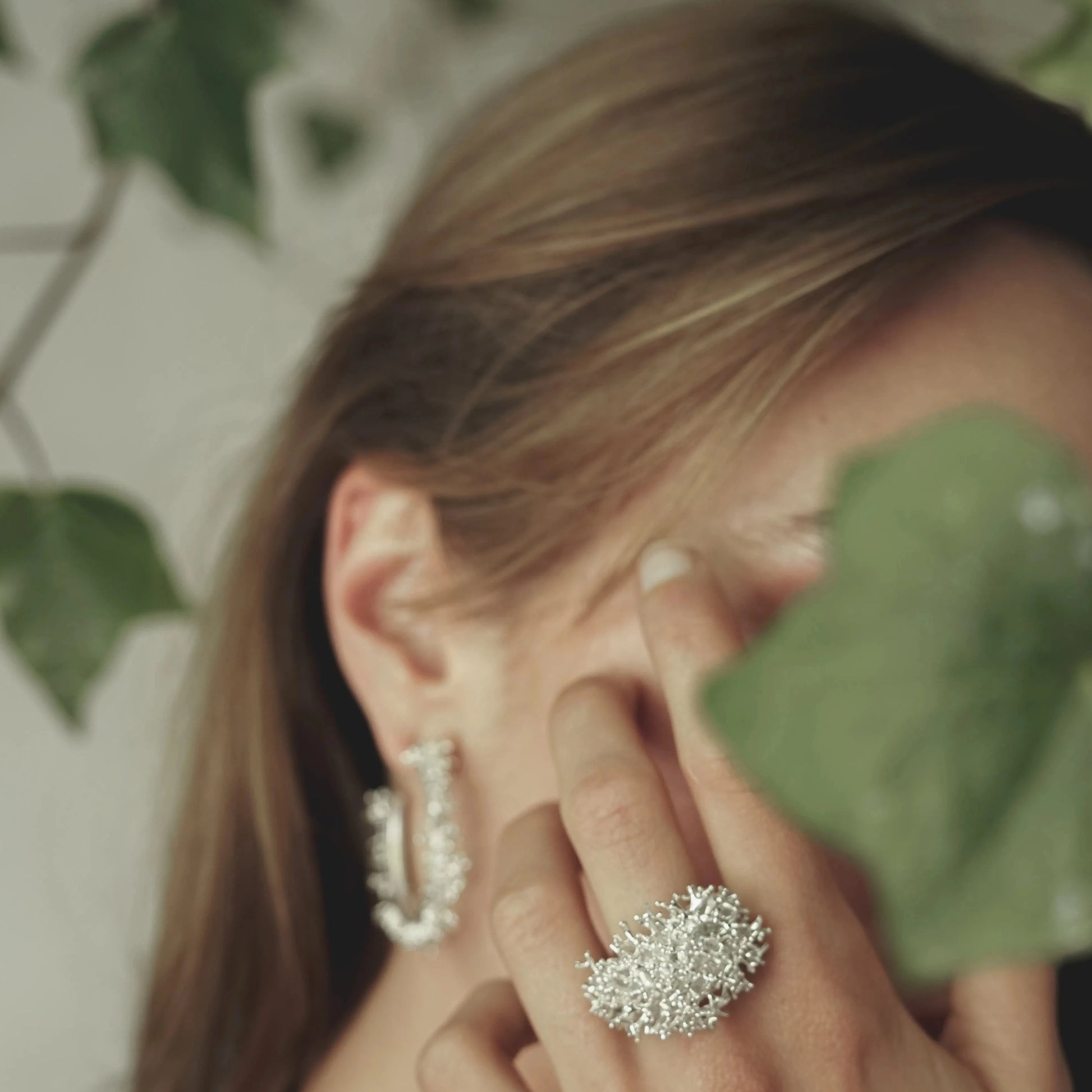 Modelo tapándose la cara con la mano mientras luce el Anillo grande Coralina en Plata.